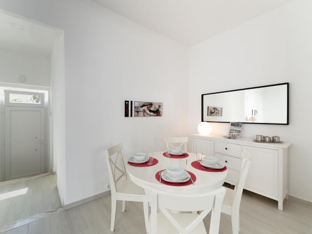 a white dining room with a white table and chairs at Casa Santos Nicolau in Setúbal