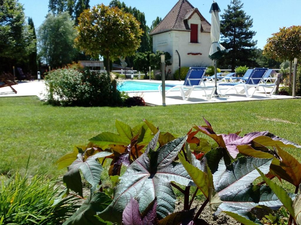 um jardim com piscina e cadeiras e uma casa em Chambres d'hôtes Au Clos de Beaulieu em Bossée