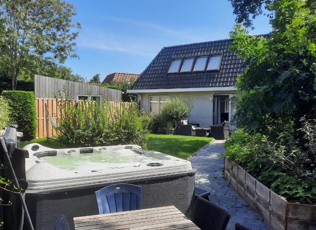 una bañera de hidromasaje en el patio trasero de una casa en Holiday Home de witte raaf with garden and hottub en Noordwijk aan Zee