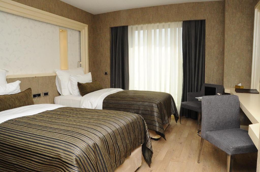 a hotel room with two beds and a desk and a chair at Limak Eurasia Luxury Hotel in Istanbul