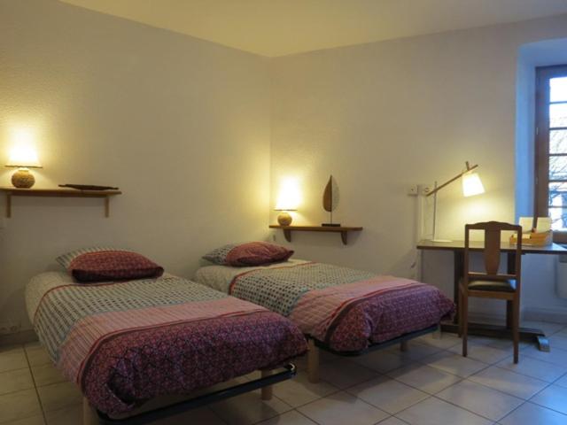 a bedroom with two beds and a desk and a chair at Au Figuier des Cévennes in Saint-Germain-de-Calberte
