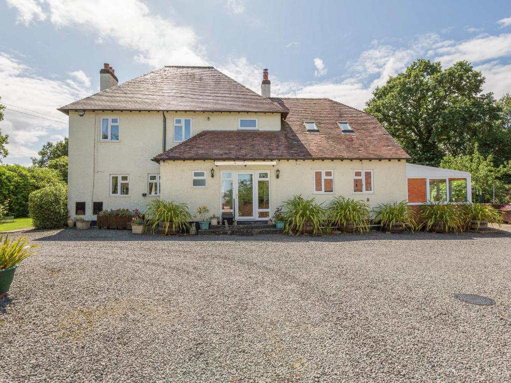 una gran casa blanca con una entrada de grava en The Big Dingle, en Church Stretton