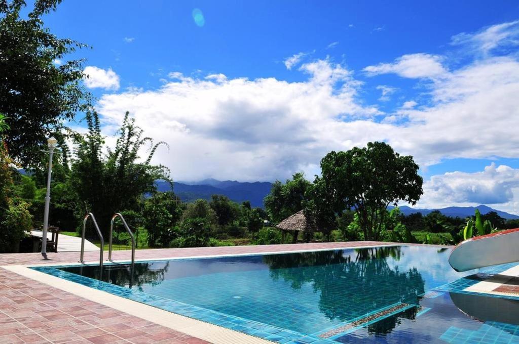 uma piscina com montanhas ao fundo em Kuad Khon Thoe Pai Cottage em Pai