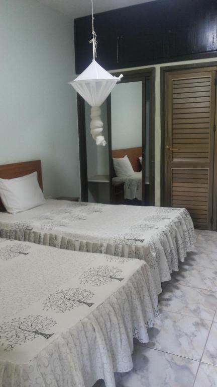 Duas camas com lençóis brancos num quarto em Sunset International Hotel em Jinja