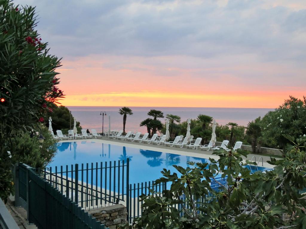 a pool with chairs and a sunset in the background at Apartment Rosy by Interhome in Costarainera