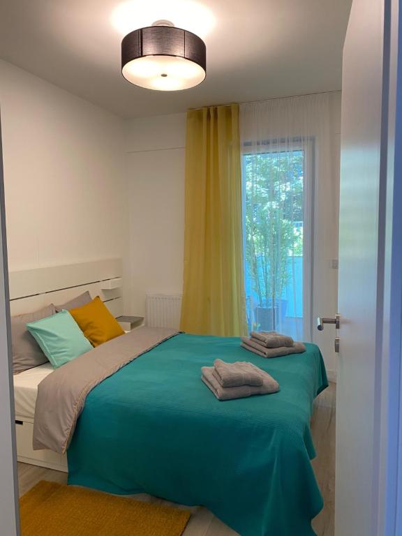 een slaapkamer met een bed met groene lakens en een raam bij Apartament Przy Plaży Rewal in Rewal