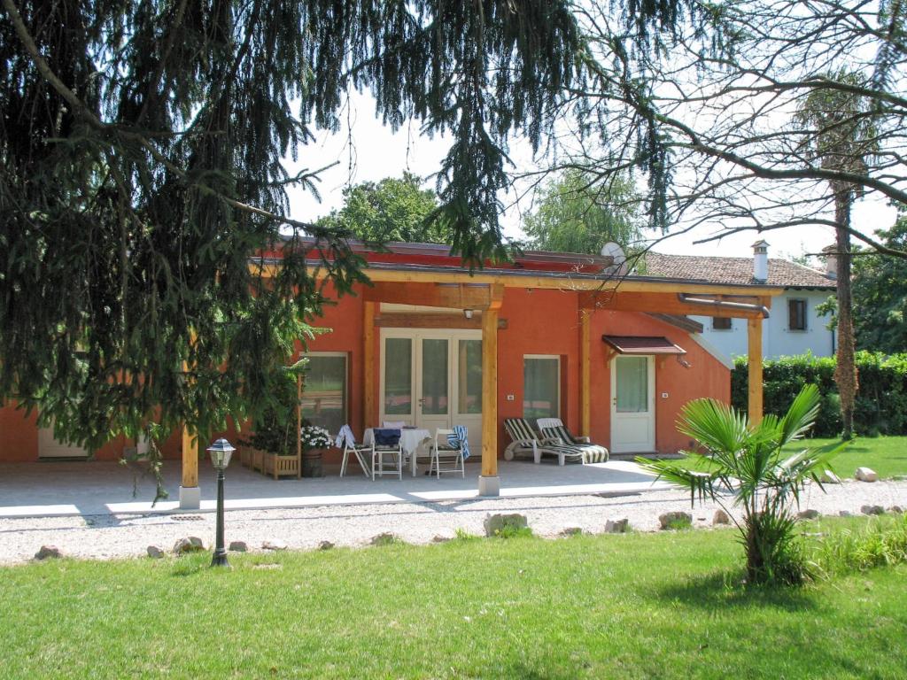 une maison rouge avec une terrasse et des chaises dans une cour dans l'établissement Apartment Winery Villa Vitas Dépendance - App-1 by Interhome, à Strassoldo