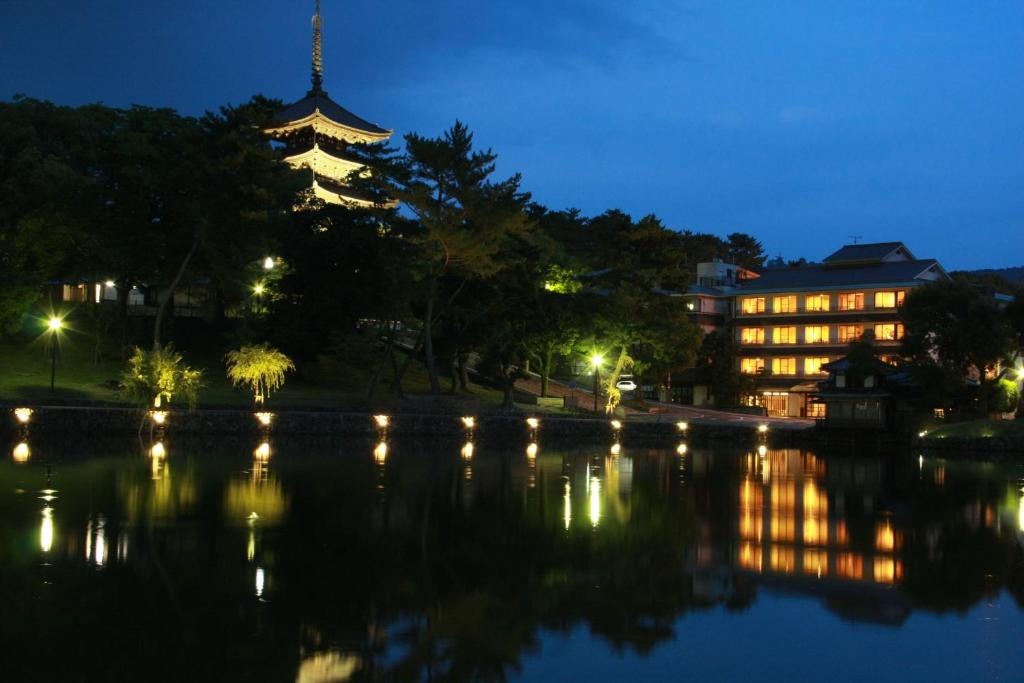 un edificio con una torre junto a un lago por la noche en Sarusawaike Yoshidaya en Nara