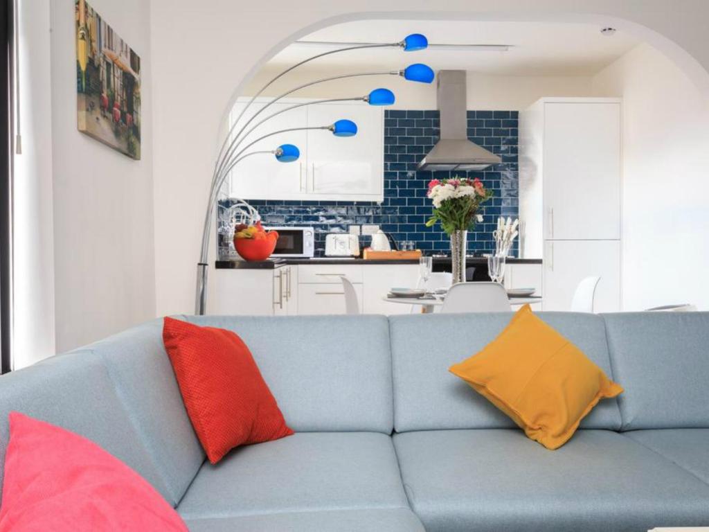 a living room with a blue couch with colorful pillows at Live in Leeds Grange Apartments in Leeds