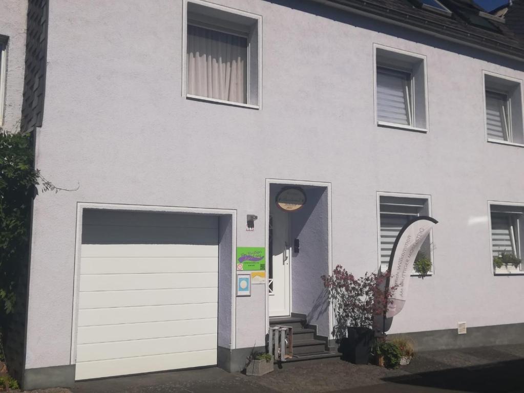 una casa blanca con una puerta de garaje blanca en Ferienwohnungen Am Bruttiger Moselsteig, en Bruttig-Fankel