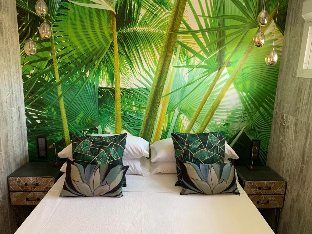 a bedroom with a bed in a room with palm leaves at Neptuno Beachfront Apartments in Marbella