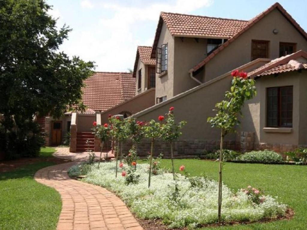 a garden in front of a house with roses at Bellstone B&B in Pretoria