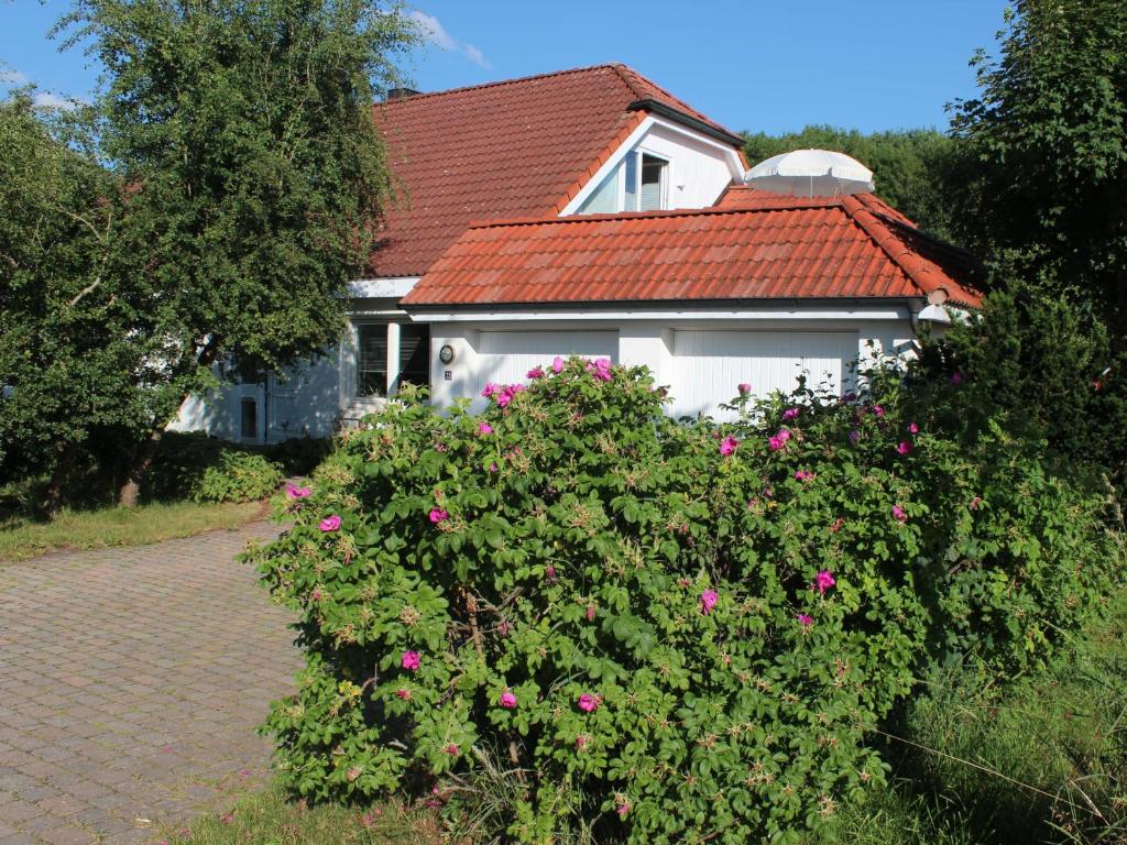 een wit huis met een rood dak en roze bloemen bij Ferienwohnung auf der Baar in Bad Dürrheim