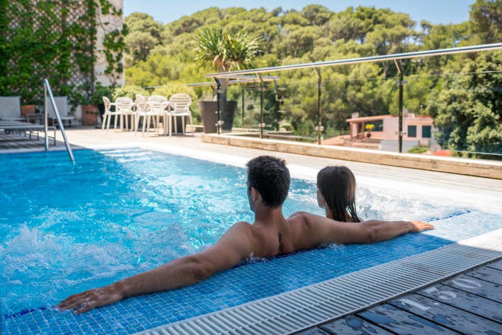 a man and a woman laying in a swimming pool at ARTIEM Audax - Adults Only in Cala Galdana