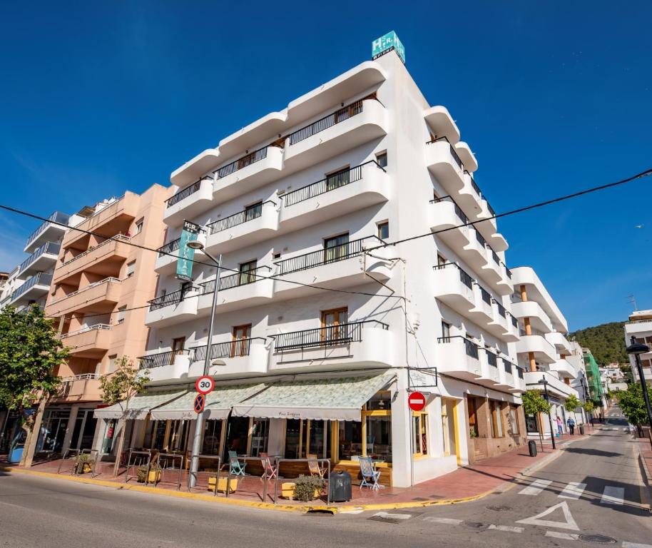 a white building on the corner of a street at Hostal y Apartamentos Santa Eulalia in Santa Eularia des Riu