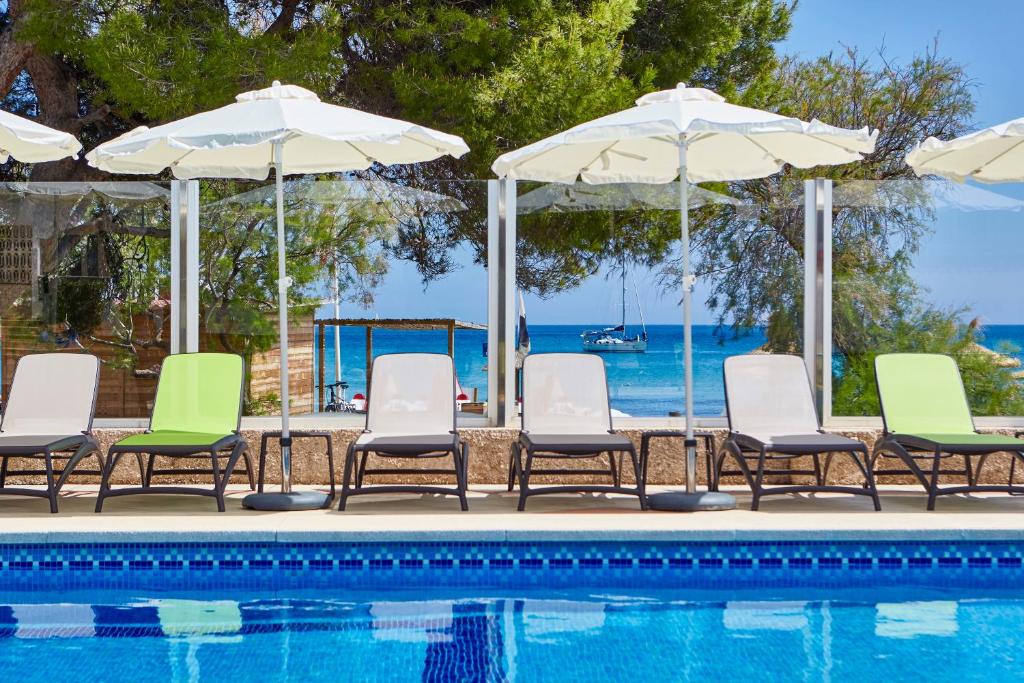 un gruppo di sedie e ombrelloni accanto alla piscina di Universal Hotel Laguna a Canyamel
