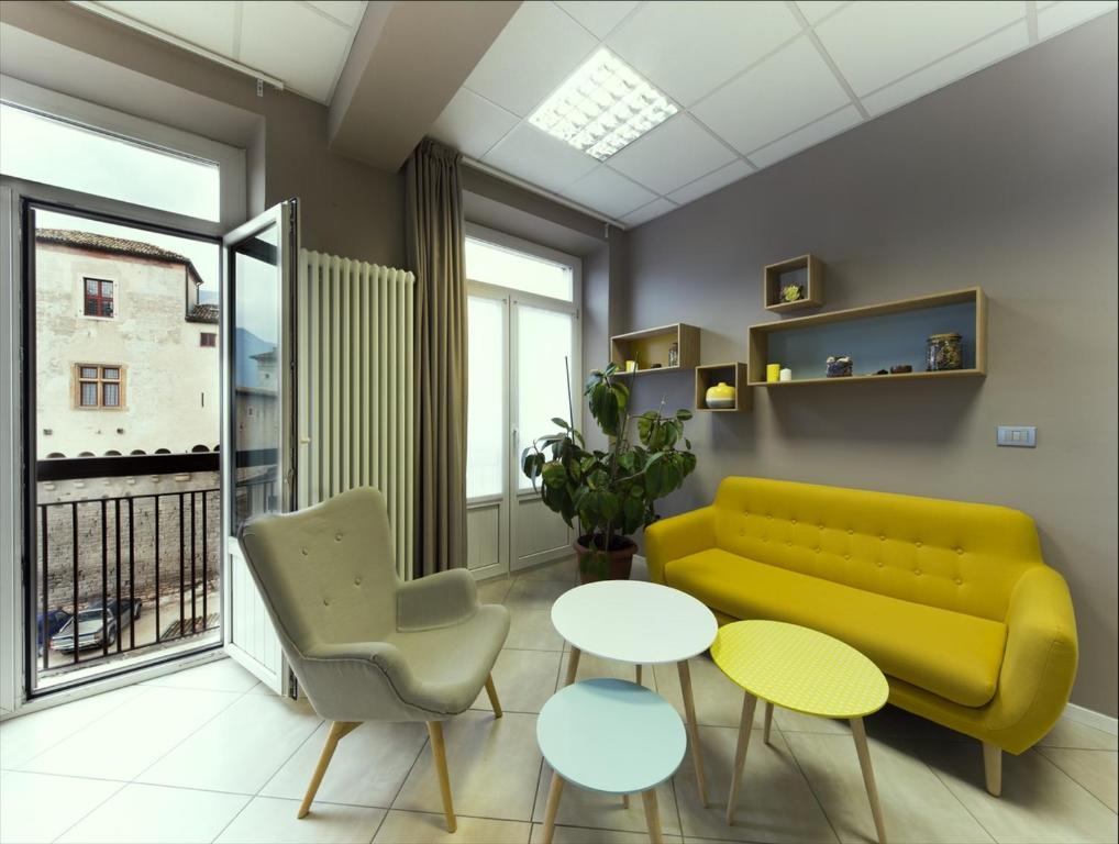 ein Wohnzimmer mit einem gelben Sofa, einem Tisch und Stühlen in der Unterkunft I Dodici mesi rooms&apartments in Trient