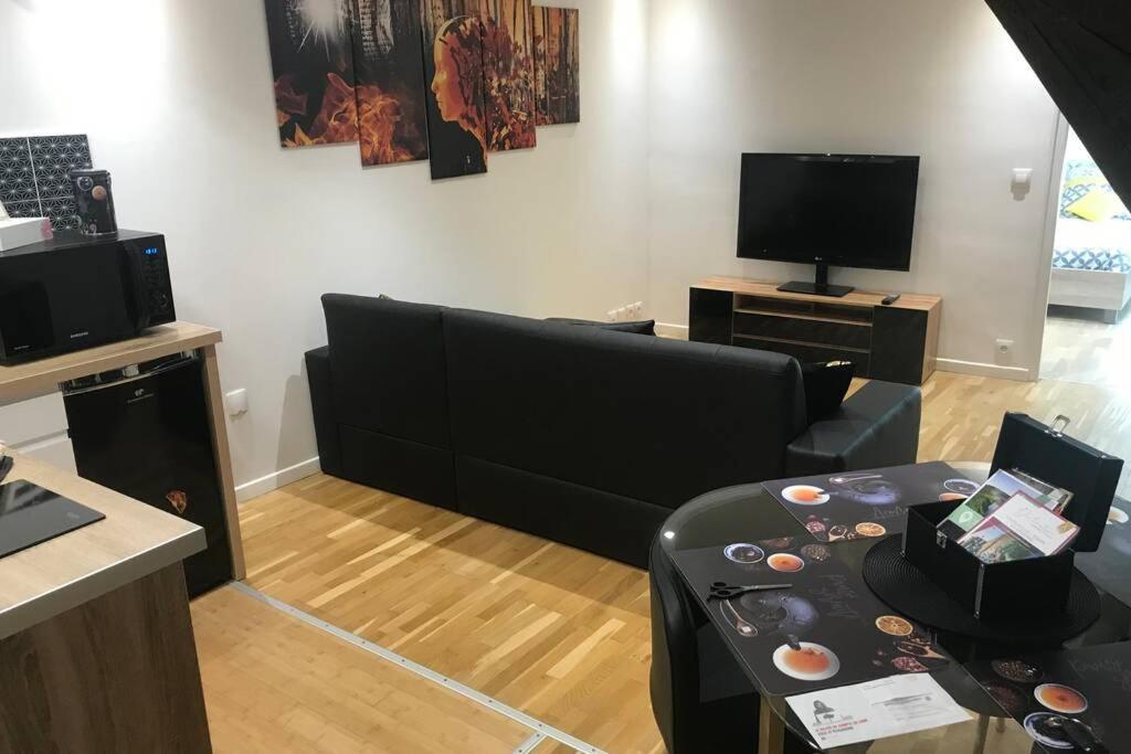 a living room with a black couch and a table at L alysé in Charleville-Mézières