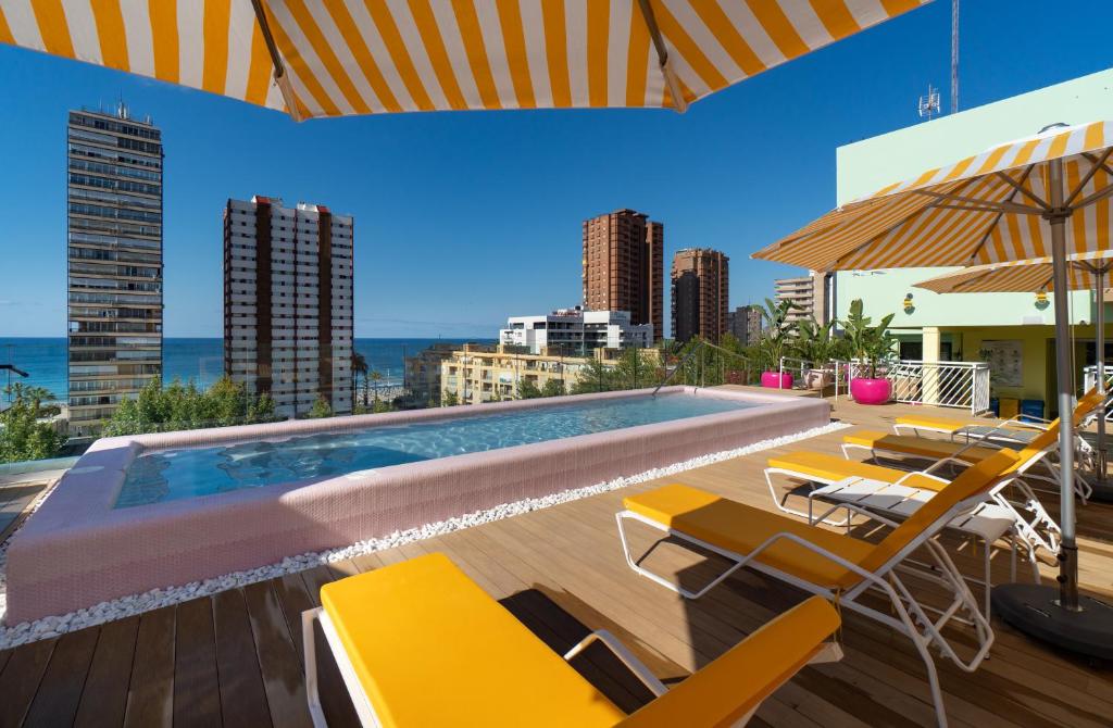 une piscine sur le toit d'un immeuble avec des chaises et des parasols dans l'établissement The Agir Springs Hotel by Medplaya, à Benidorm