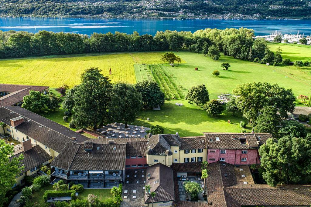 una vista aérea de una casa con un campo y agua en Castello del Sole Beach Resort&amp;SPA, en Ascona