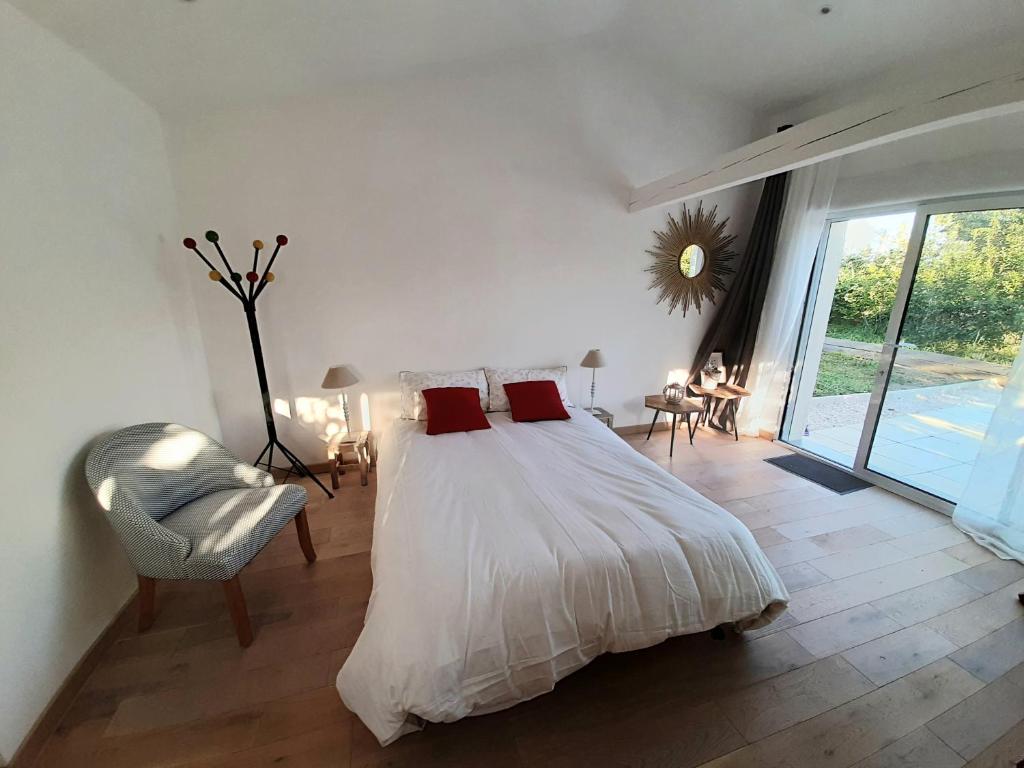 una camera da letto con un letto con cuscini rossi e una sedia di Studio équipé indépendant chaleureux lumineux a Saubens