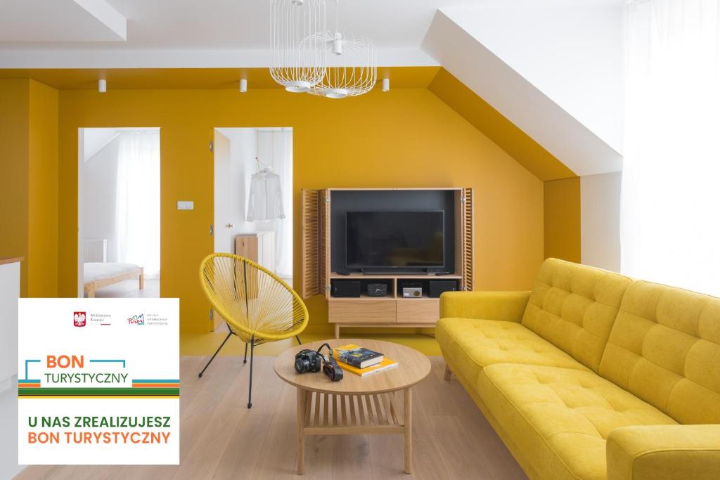 uma sala de estar com um sofá amarelo e uma televisão em Colors Apartments Zator - tylko 10 minut piechotą od Energylandii em Zator