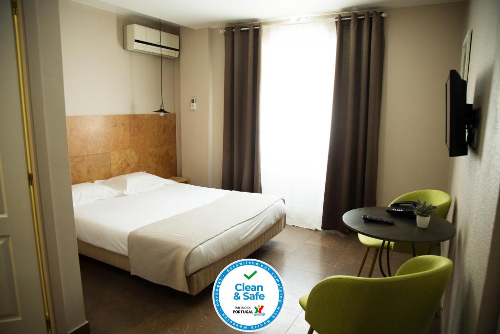 um quarto de hotel com uma cama, uma mesa e cadeiras em Hotel Laitau em Setúbal
