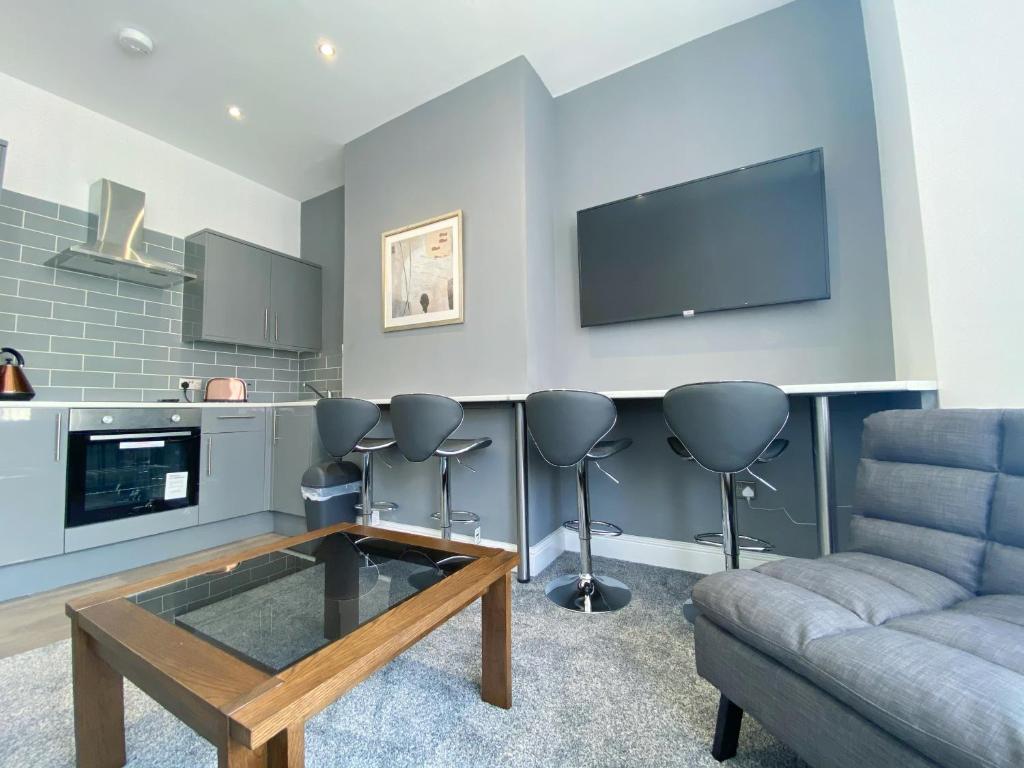 a living room with a couch and a flat screen tv at Mayfair Suite Sasco Apartments in Blackpool