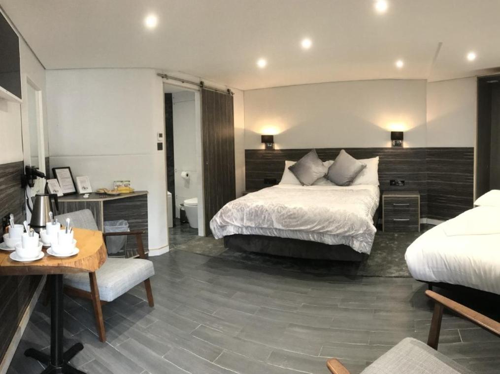 a hotel room with a bed and a desk and a bed and a table at The WatersEdge, Canal Cottages in Hillingdon