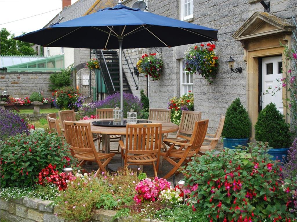 a table and chairs with an umbrella in a garden at Double-Gate Farm in Wells