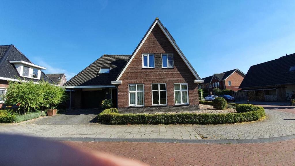 ein braunes Backsteinhaus mit weißen Fenstern auf einer Straße in der Unterkunft Logies bij Wandelpad te Holten in Holten