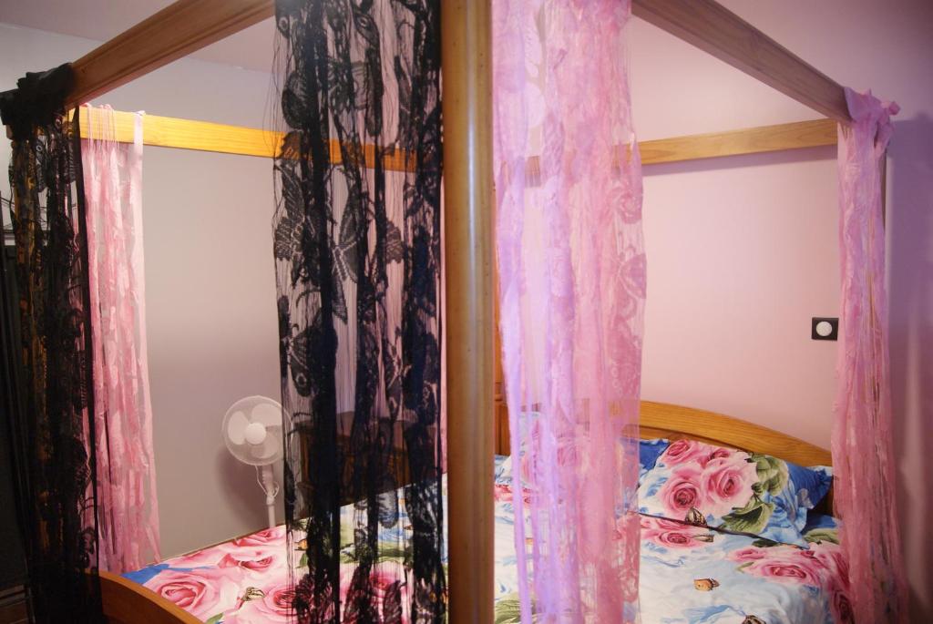 um quarto com uma cama de dossel e cortinas cor-de-rosa em Gite de Rose Blanche em Belle-et-Houllefort