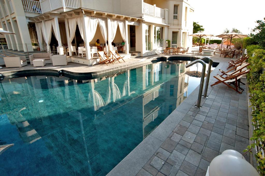 a large swimming pool with chairs and a building at Le Rose Suite Hotel in Rimini