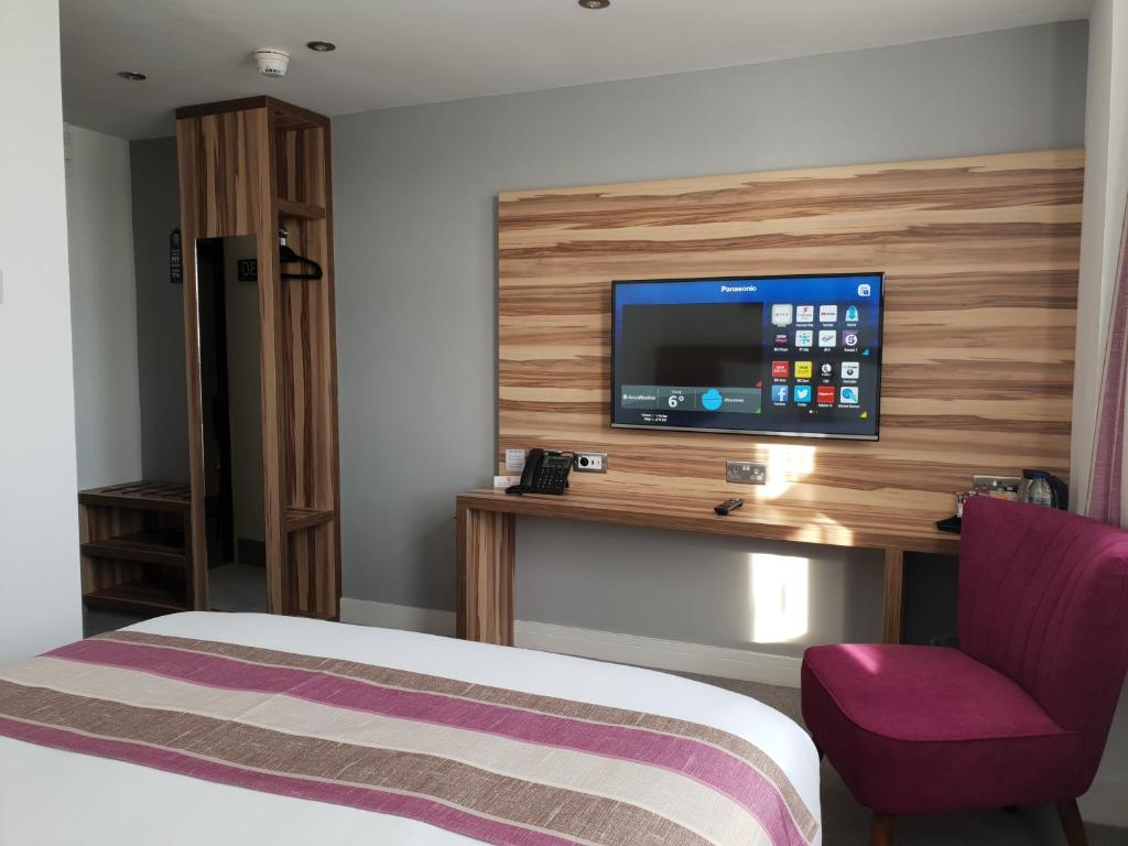 um quarto de hotel com uma cama e uma televisão na parede em Escape Hotel em Barrow in Furness