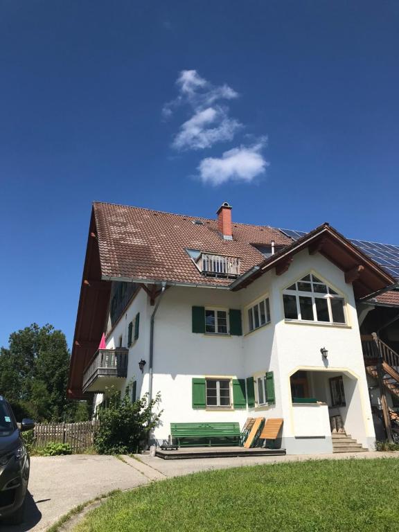 ein weißes Haus mit braunem Dach in der Unterkunft Ferienwohnung mit Alpenblick in Antdorf