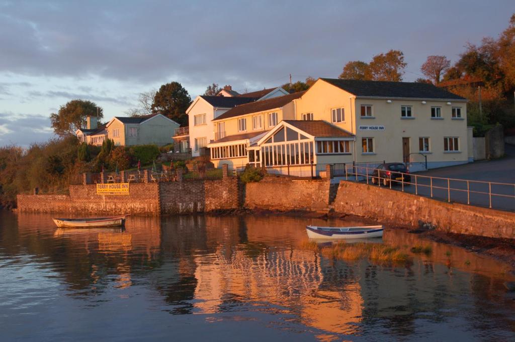 two boats in the water in front of houses at Ferry House Inn in Milford Haven