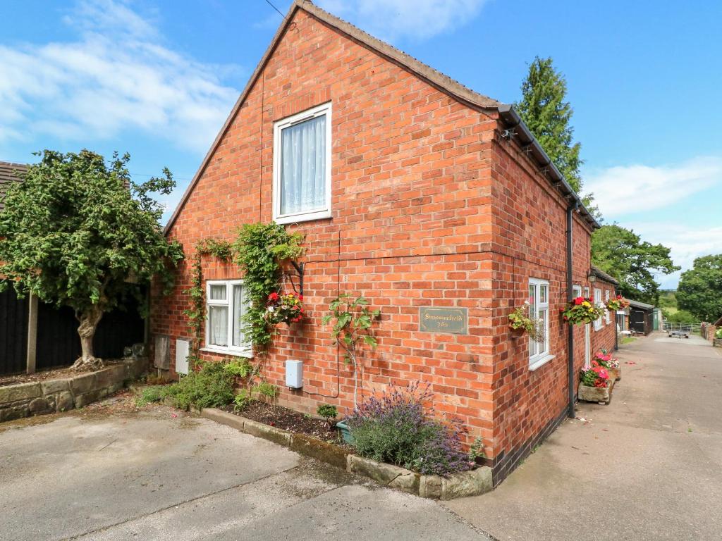 une maison en briques avec des fleurs sur son côté dans l'établissement Summerfields, à Uttoxeter