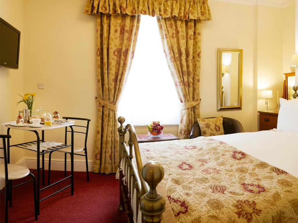 ein Hotelzimmer mit einem Bett, einem Tisch und einem Fenster in der Unterkunft Filey Grange in Filey