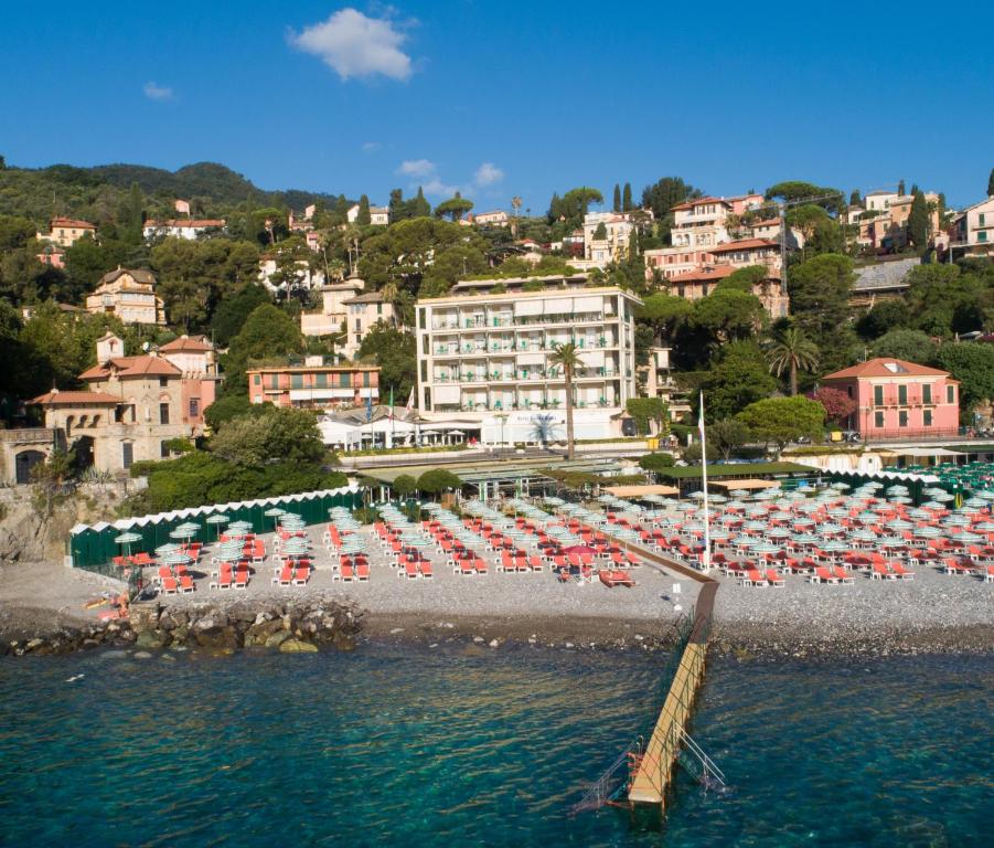 una playa con sillas y sombrillas en el agua en Best Western Regina Elena en Santa Margherita Ligure