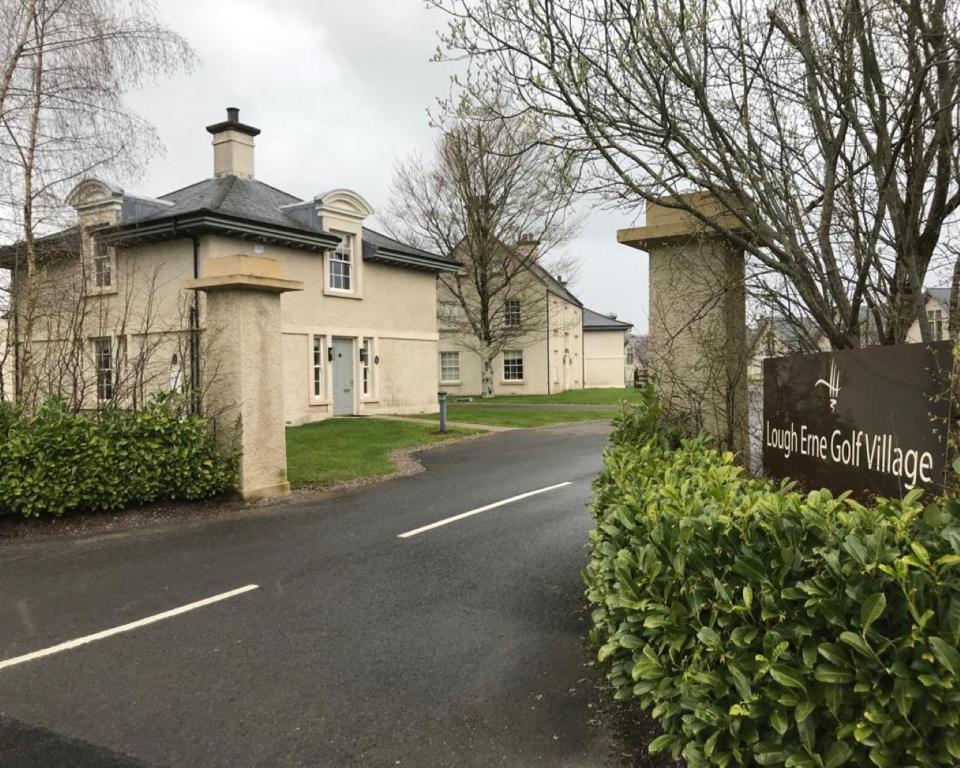 uma casa com um sinal que lê a sua grande e velha aldeia em Gate lodge at Lough Erne Golf Village em Ballycassidy