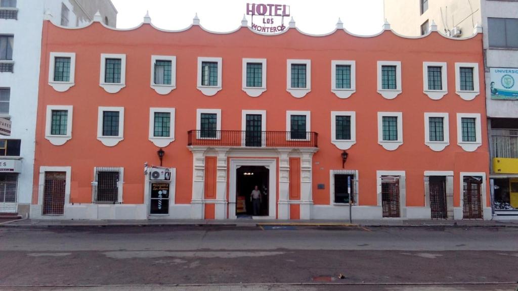 シウダービクトリアにあるHotel Los Monterosの白い柱と窓のある大きなオレンジ色の建物