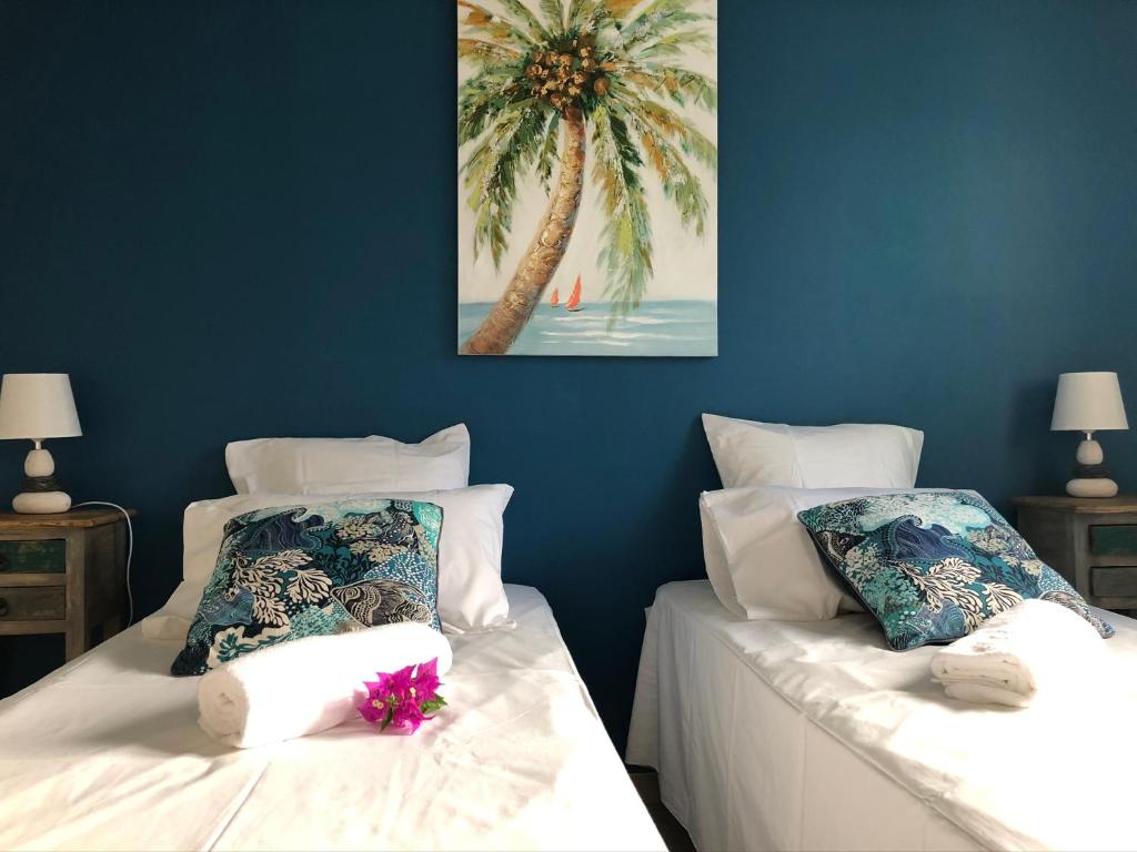 2 camas en una habitación con una palmera en Appartement de charme au bord de mer, en Saint-François