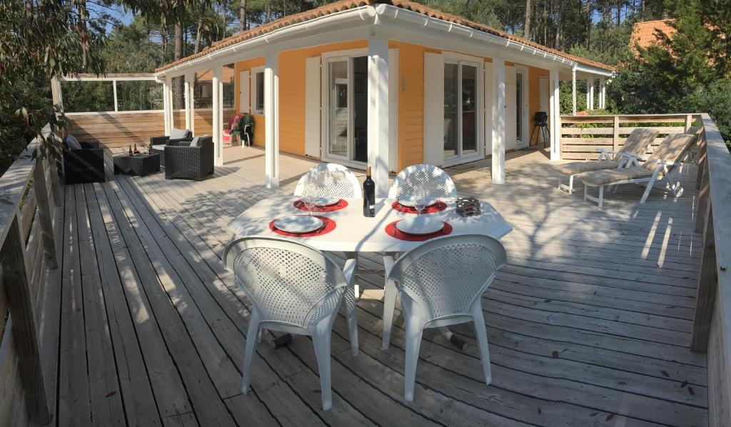 a table and chairs on a deck with a house at Chalet orange naturiste la Jenny in Le Porge