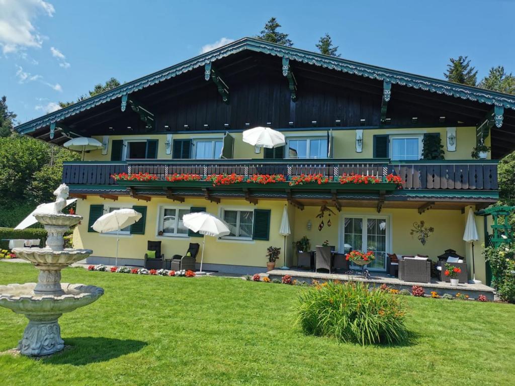 a large yellow building with a fountain in front of it at Ferienwohnungen Thalmeier in Sankt Gilgen