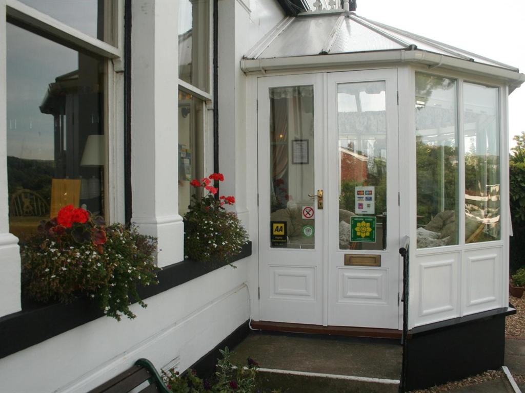 une porte d'entrée blanche d'un immeuble avec des fleurs dans l'établissement Glan Heulog, à Conwy