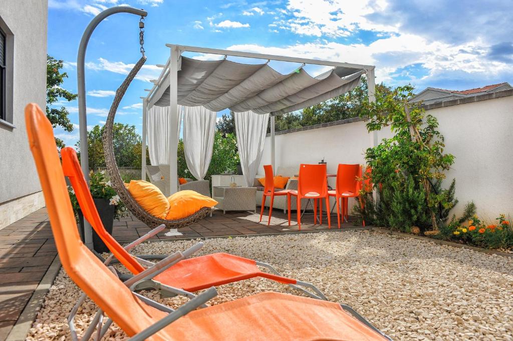 een patio met oranje stoelen en een parasol bij APARTMENT SECRET GARDEN 2 in Zaton