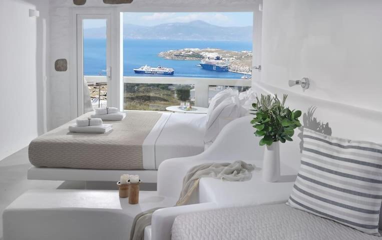 a white bedroom with a bed and a view of the ocean at Crystal Suites in Mikonos