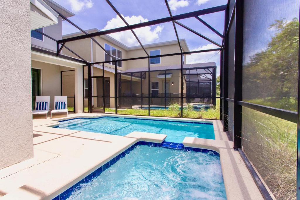 an indoor swimming pool with a view of a house at Stunning 5 Bd w/ Pool Close to Disney @ Storey Lake 2767 in Kissimmee