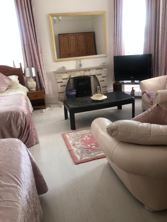 
a living room filled with furniture and a tv at Brown's Guest House in Peterhead
