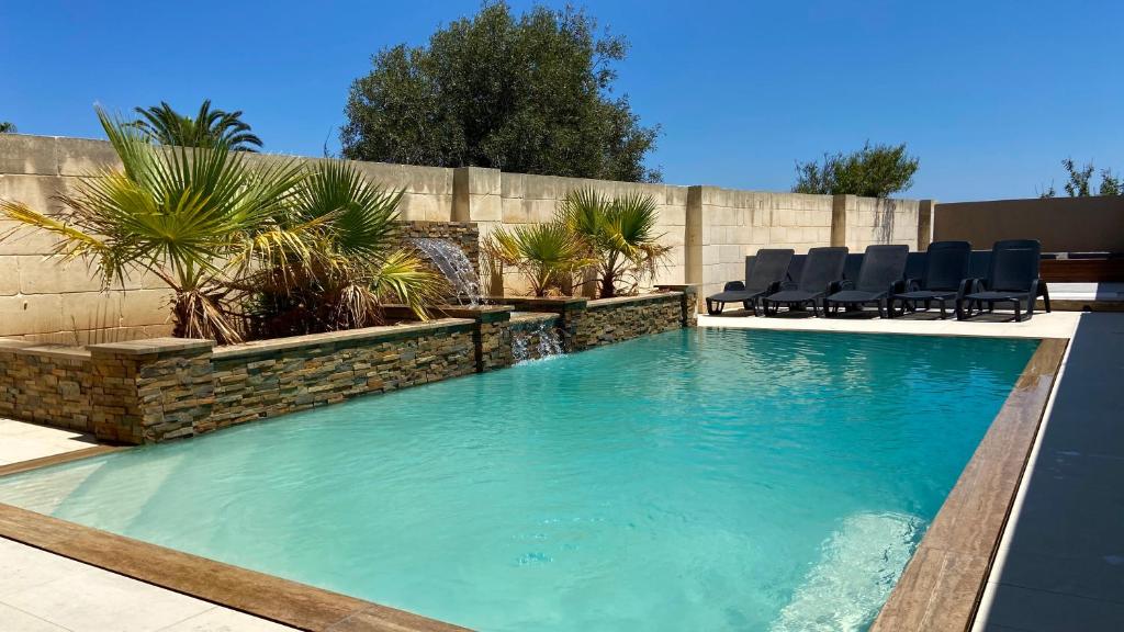 una piscina con sillas en un patio trasero en Ta Lucija - Luxurious 6 Bedroom/En suite Villa - Pool / AC, en Santa Luċija